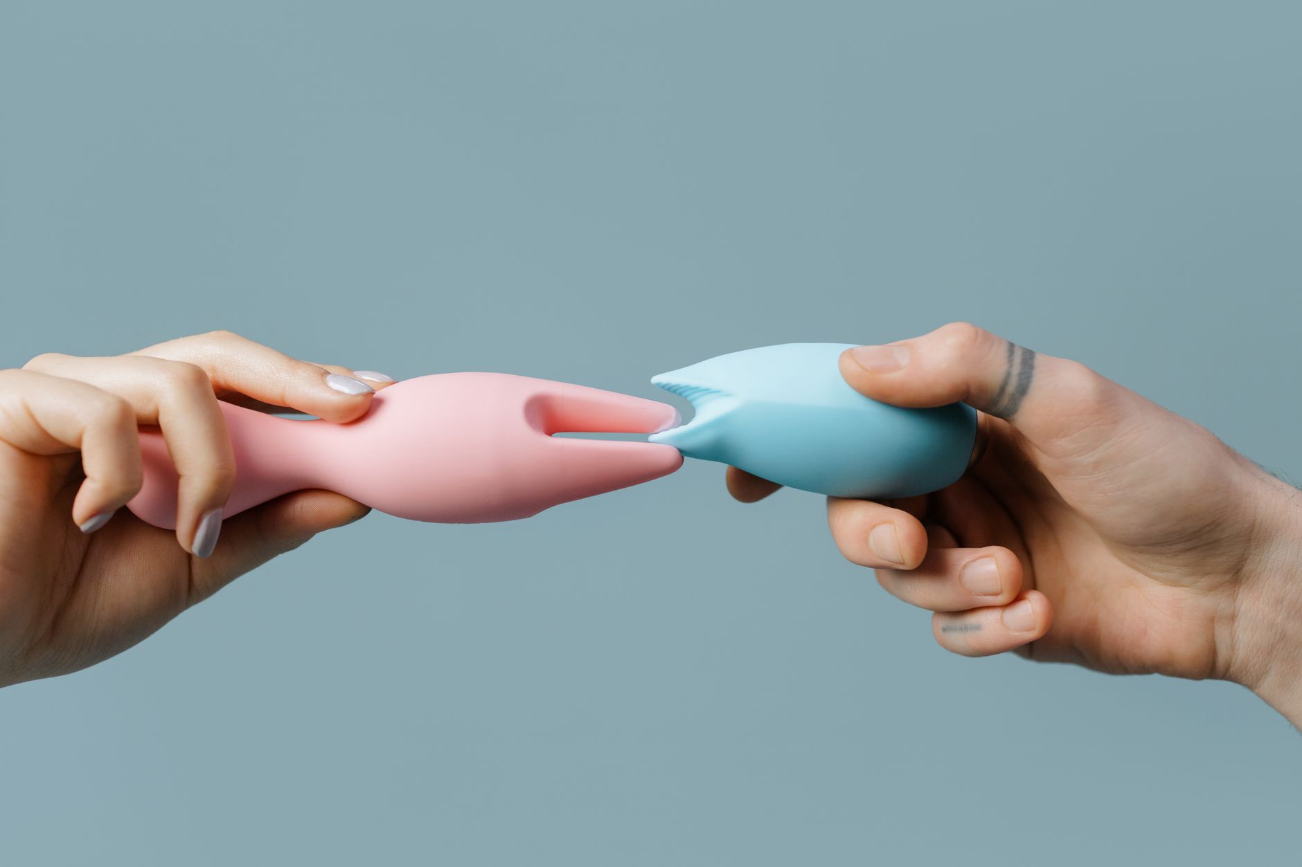 Hands holding pastel-colored silicone vibrators including lemon clitoral toys