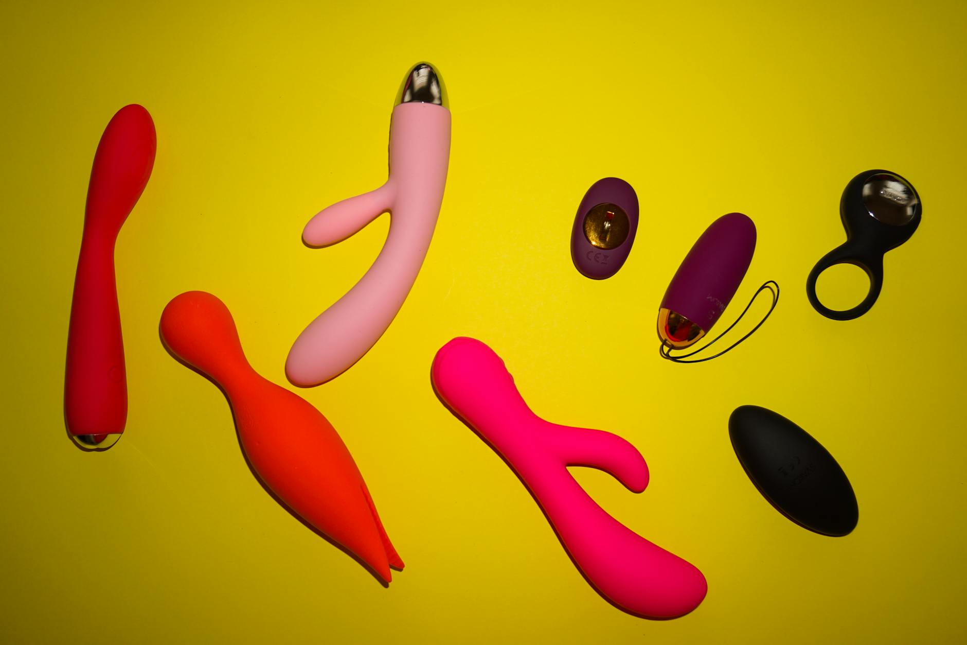 Vibrant display of colorful vibrators and wellness devices on a bright yellow surface